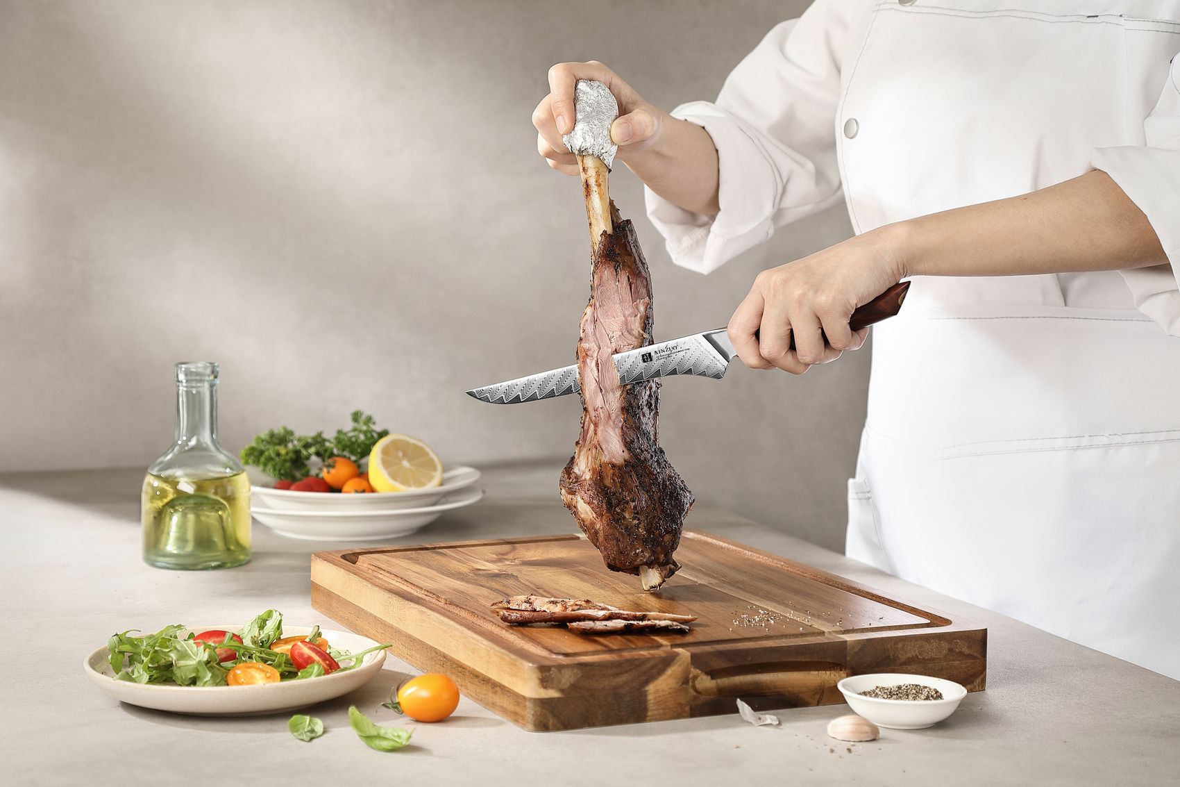 Chef boning a roasted lamb leg, the curved Damascus boning knife working the meat away from the bone on a wood board