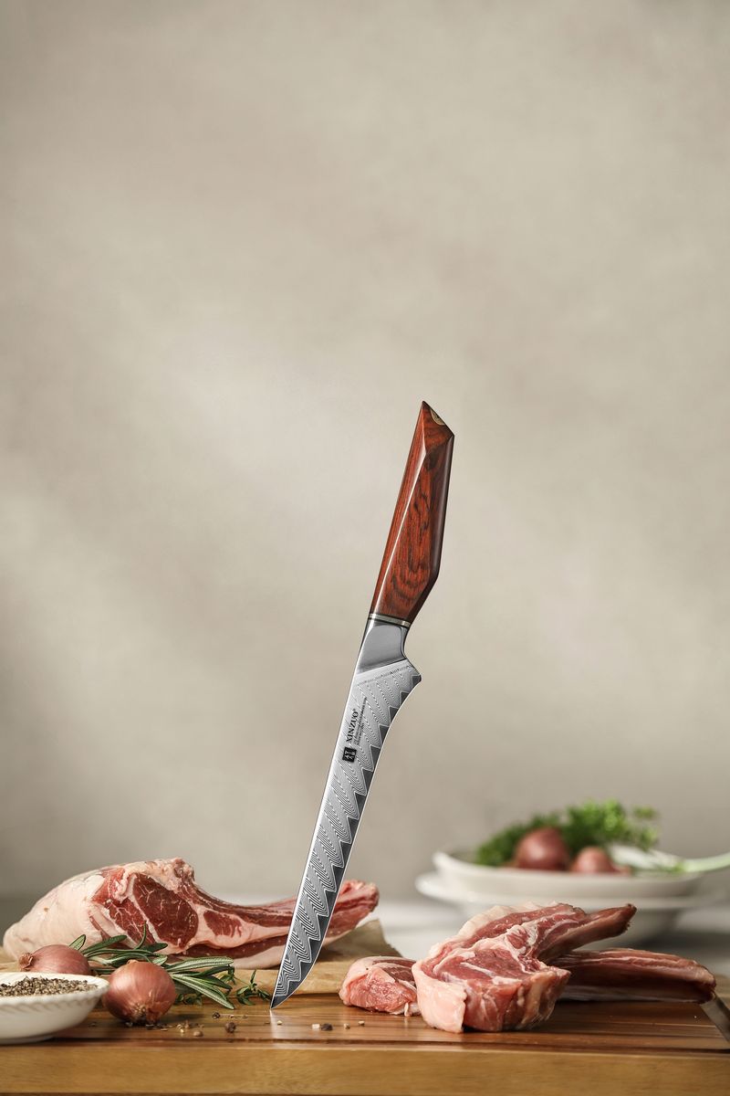 Studio shot of the XINZUO boning knife standing upright, showing the curved Damascus-pattern blade and rosewood handle above raw lamb chops