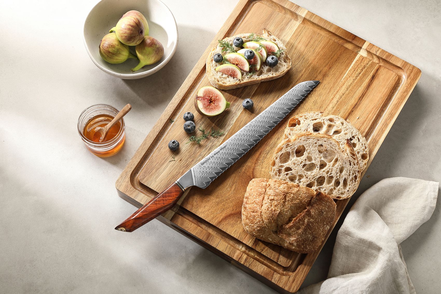 Bread knife on a wooden board with sliced sourdough, fresh figs and honey