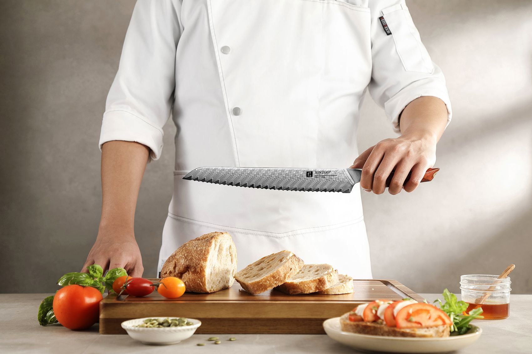 Chef in white uniform holding the Damascus bread knife above a board of sliced bread