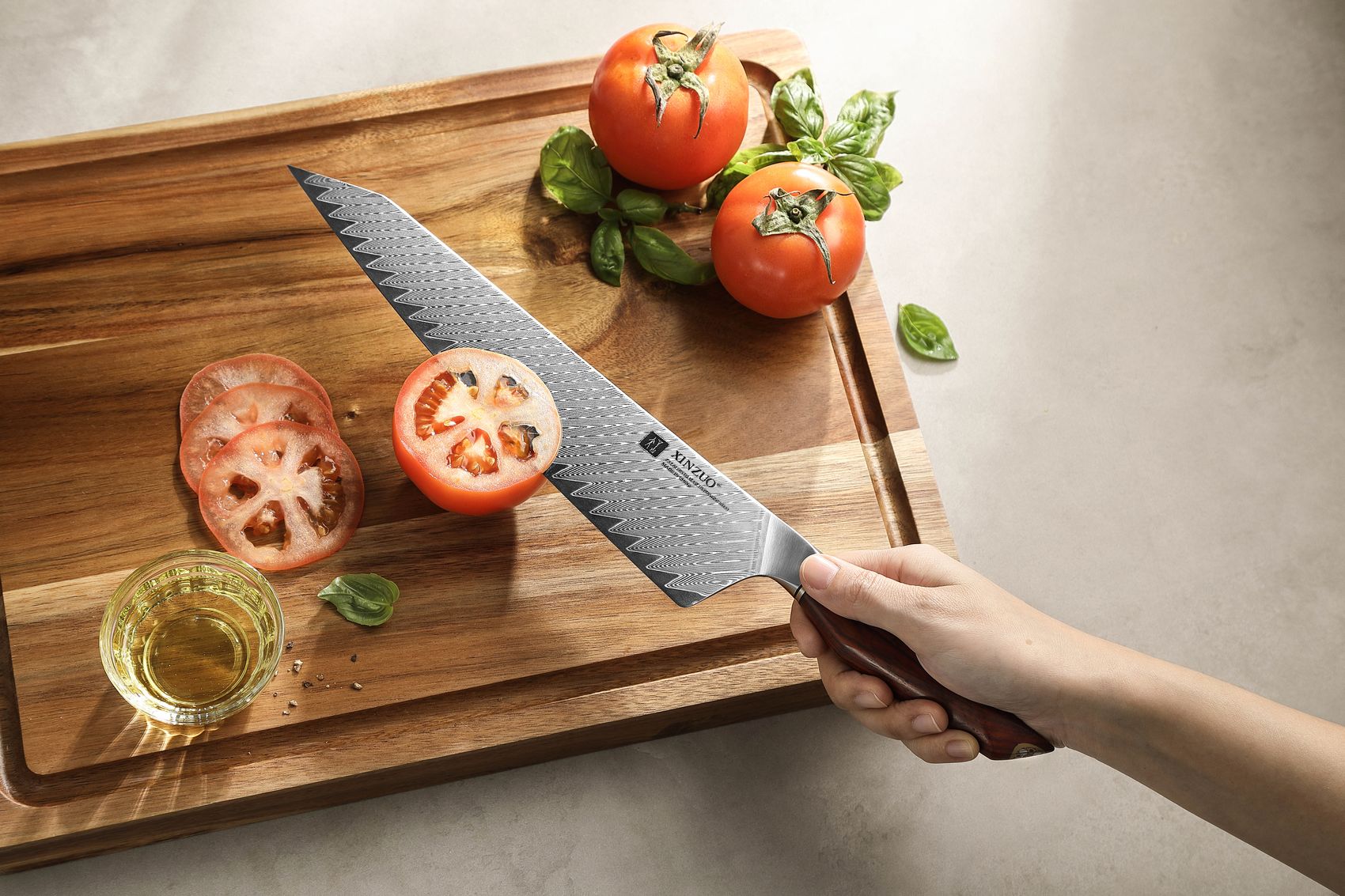 Hands using the 10-inch Damascus chef knife to slice ripe tomatoes on a wooden board