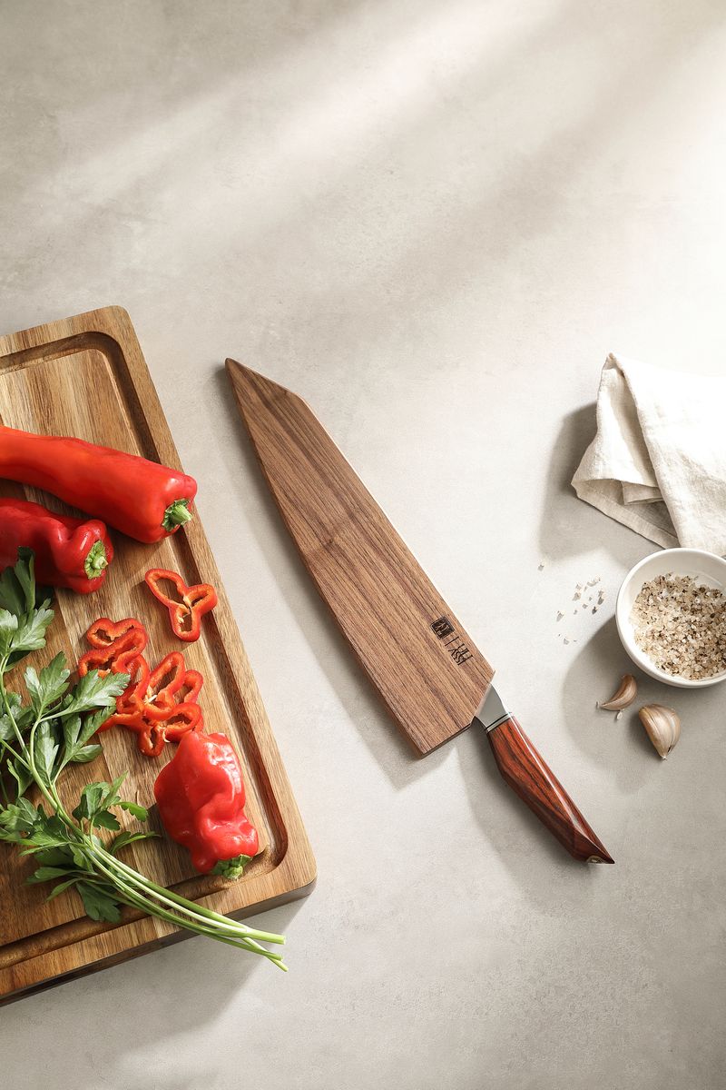 Wooden saya sheath alongside the 10-inch chef knife with red peppers and herbs