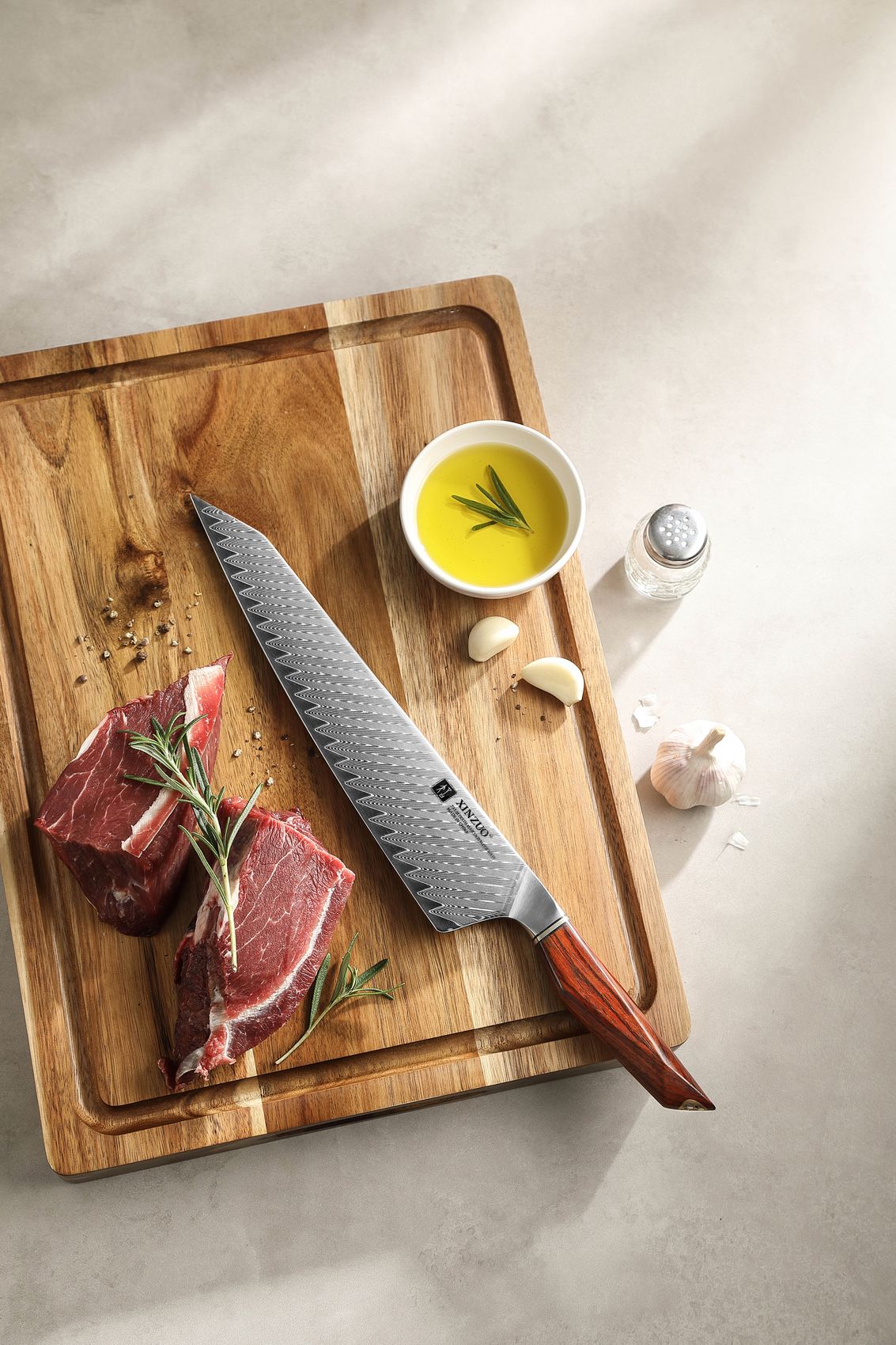 The 10-inch Damascus chef knife on a wooden board with raw steak, olive oil and garlic