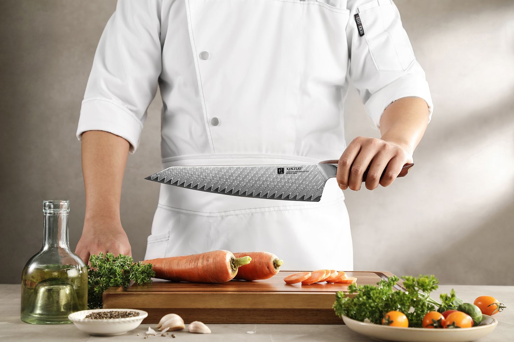 Chef in whites holding the 10-inch Damascus chef knife beside fresh carrots and herbs