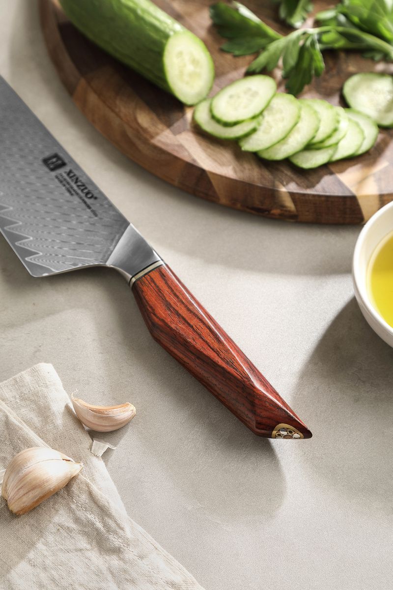 Studio detail of the Damascus steel blade and rosewood handle of the 10-inch chef knife