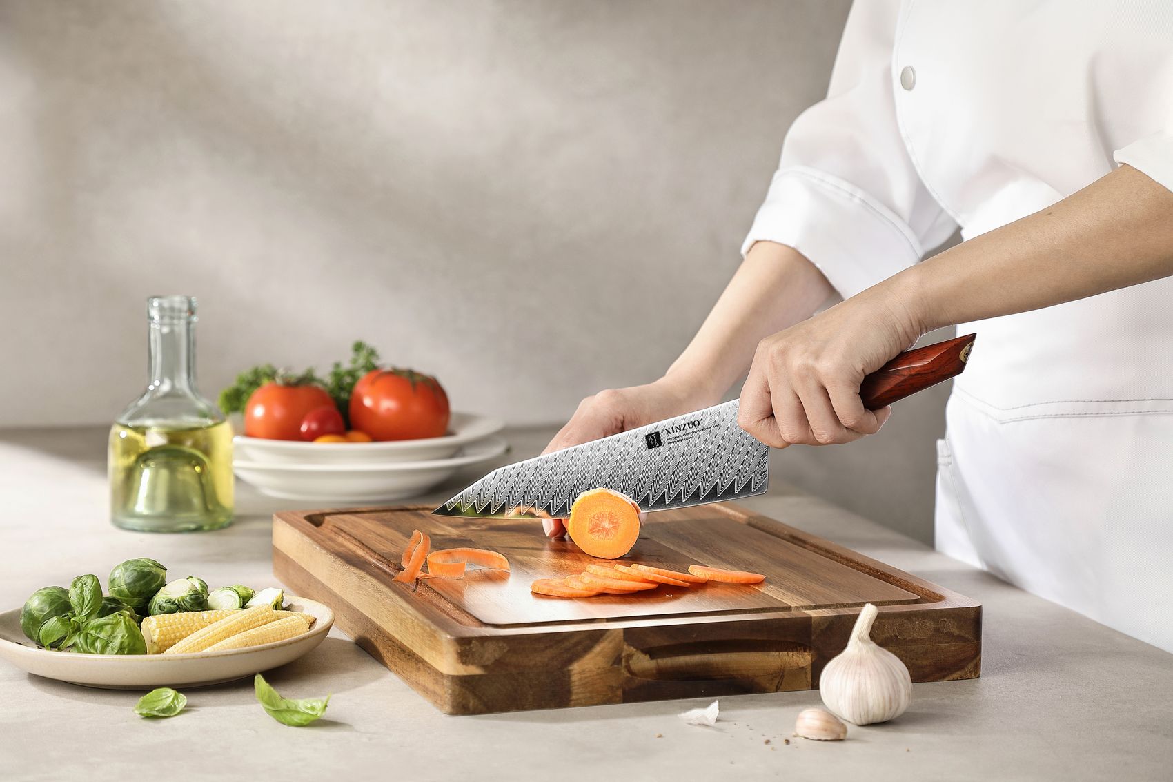 Chef in whites slicing carrot on a board using the Damascus bunka chef knife