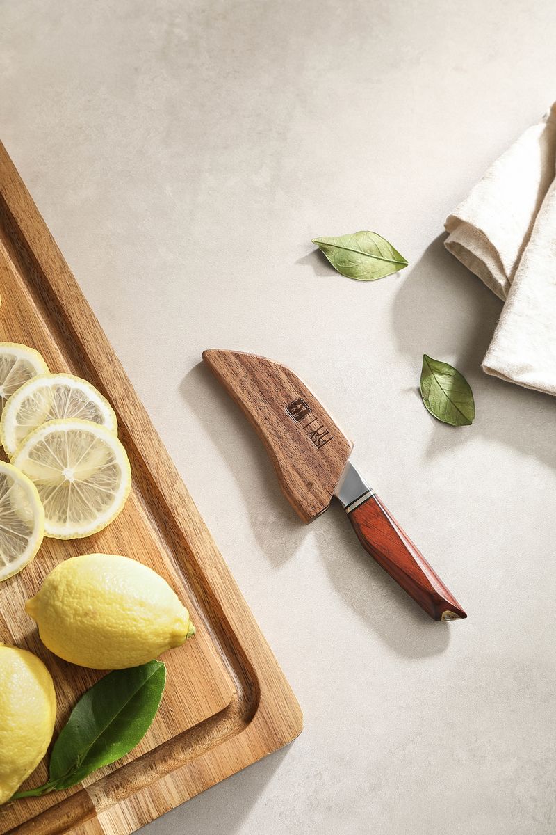 Paring knife sheathed in its wooden saya cover beside sliced lemons on a cutting board