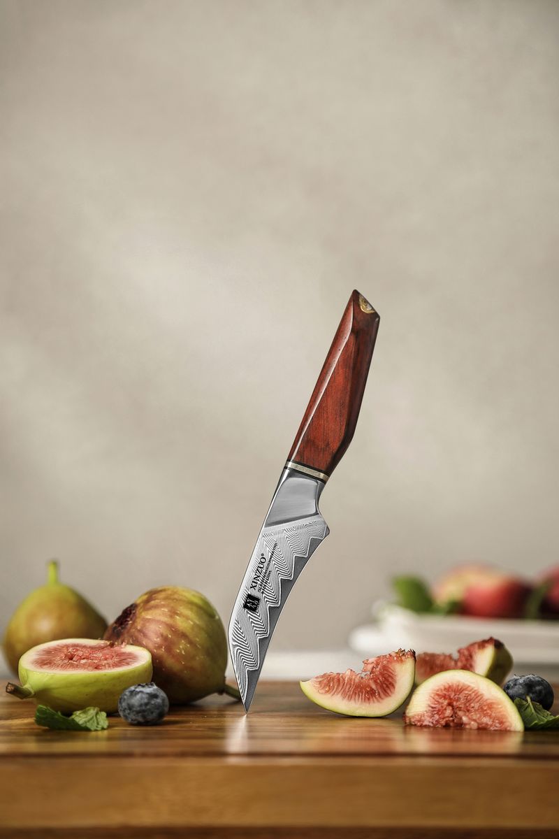 Studio shot of the paring knife standing upright showing the full Damascus blade pattern and rosewood handle