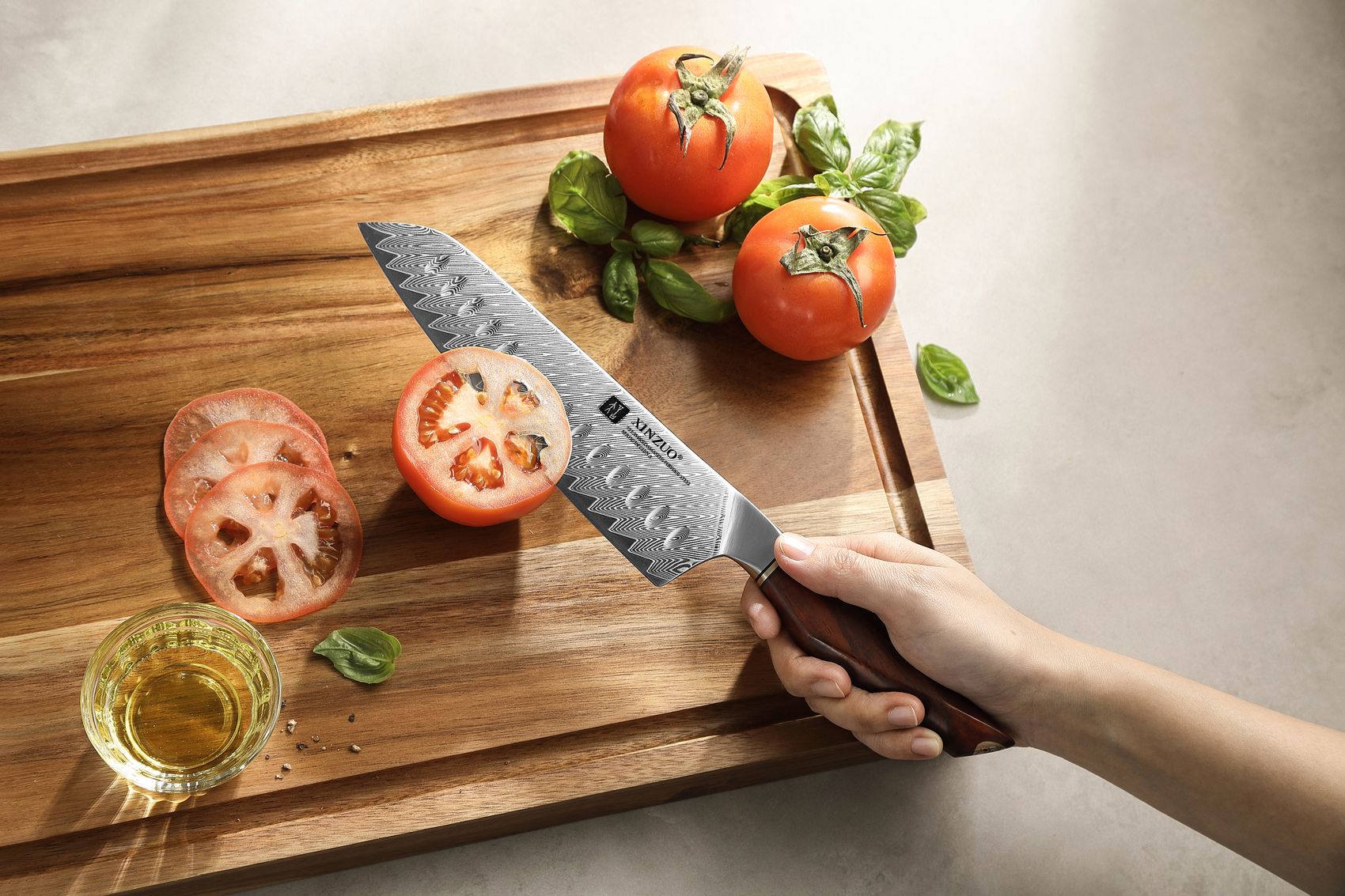Overhead view of the Damascus Santoku knife slicing a ripe tomato on a wooden cutting board