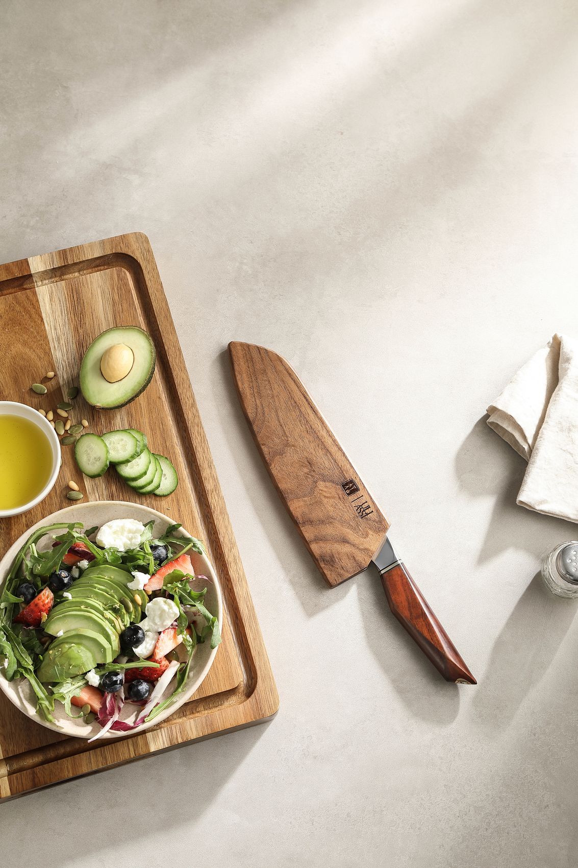 The Santoku knife sheathed in its wooden saya beside a board of salad ingredients