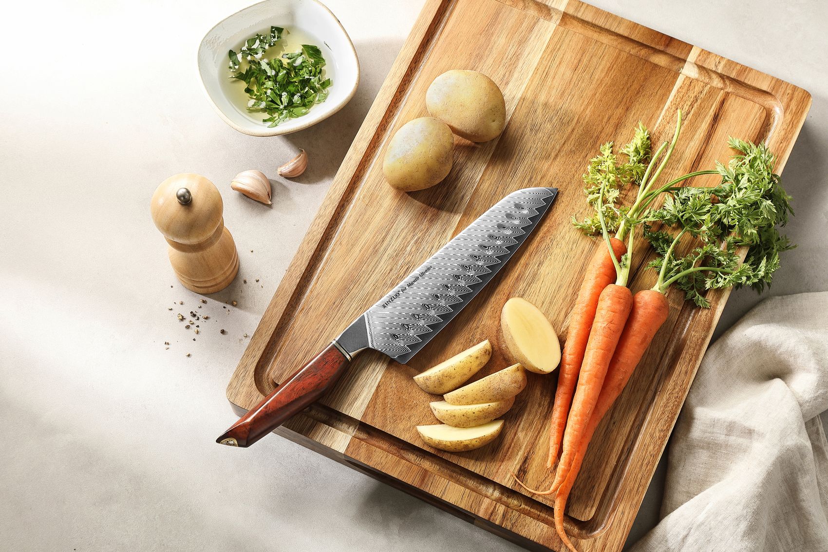 The Santoku knife on a wooden board with carrots and potatoes ready to be prepped