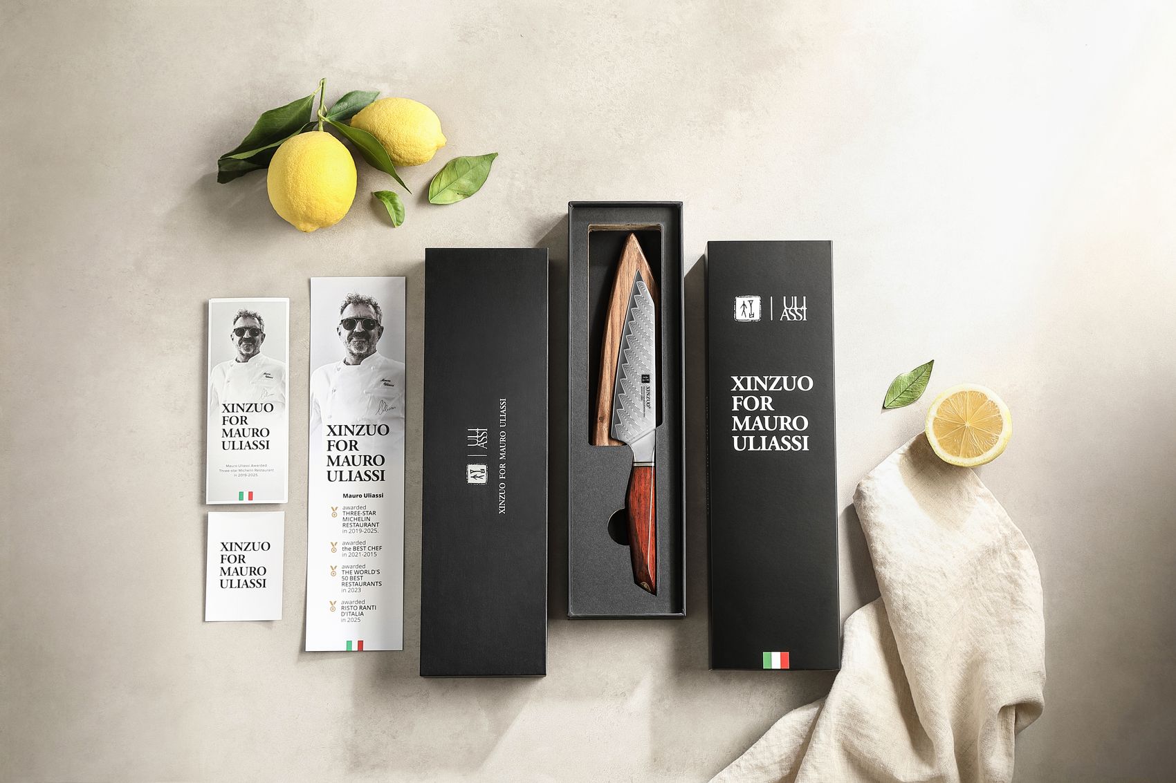 XINZUO for Mauro Uliassi gift box set with the Damascus utility knife seated in foam, branded outer sleeve, chef booklet and fresh lemons